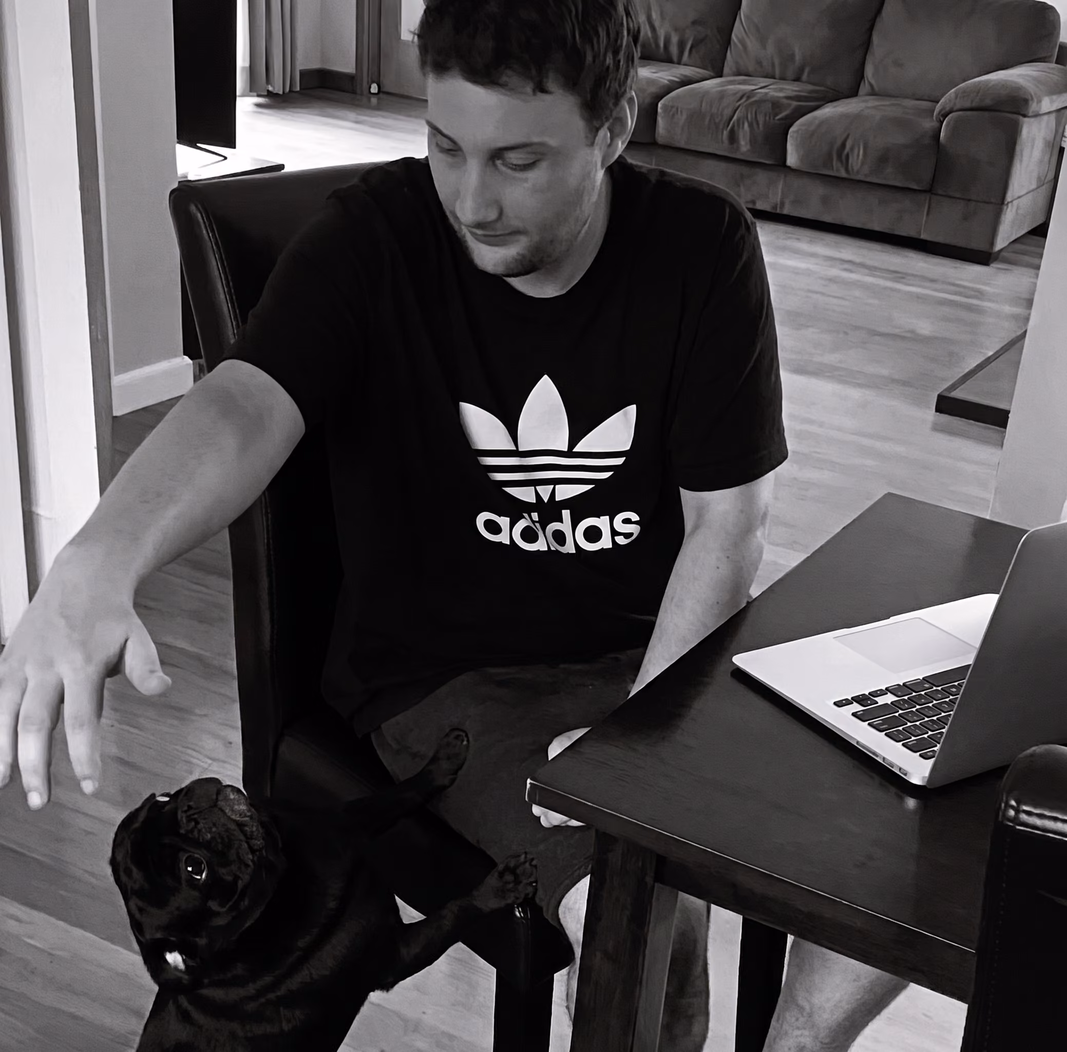 Black and white image of Aaron Goodwin with his dog Bentley, a black pug, at their former home in Christchurch.